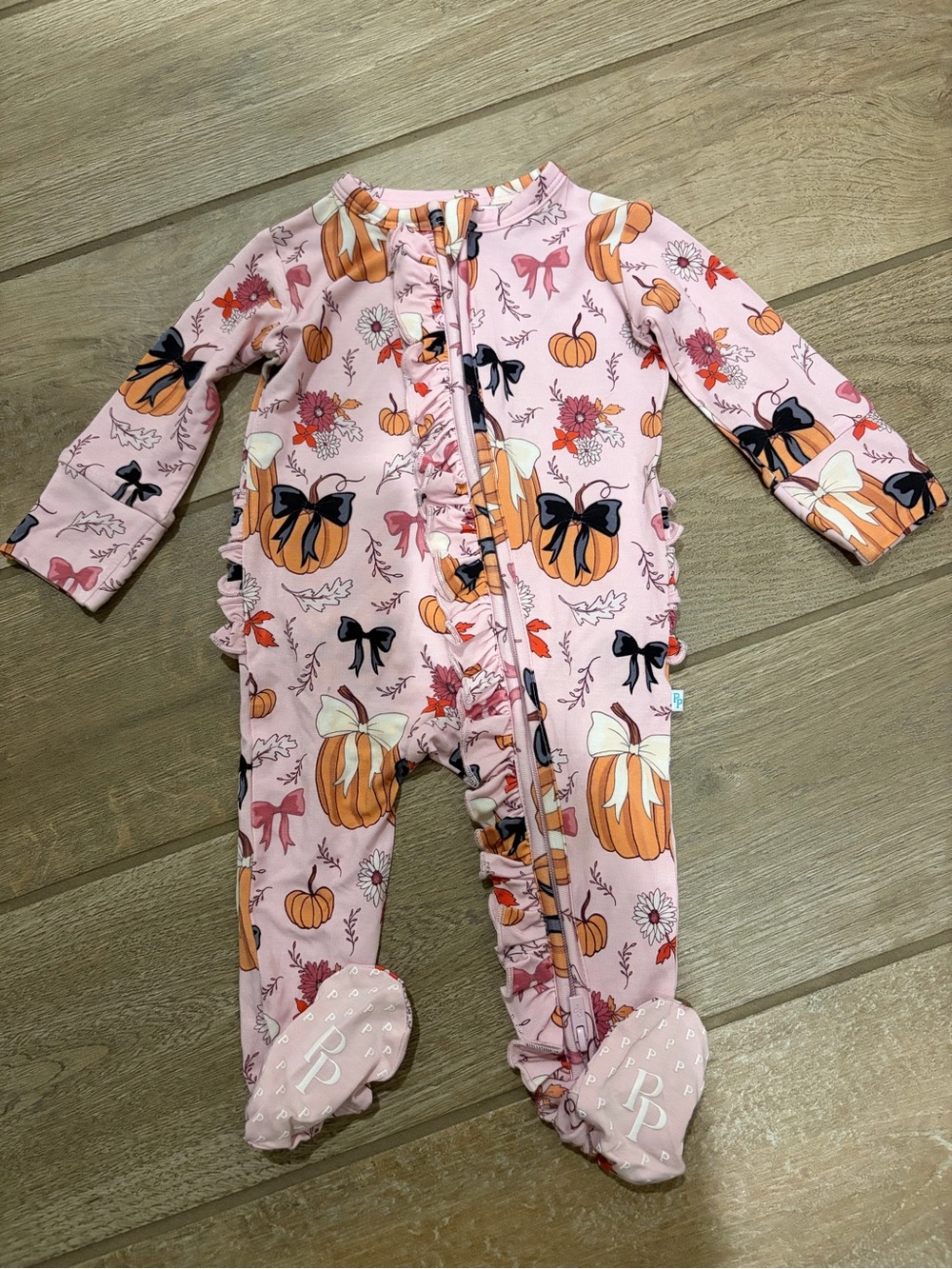 Posh Peanut ruffle footie features a pink "Regan" pumpkin and bow pattern 0-3 mo